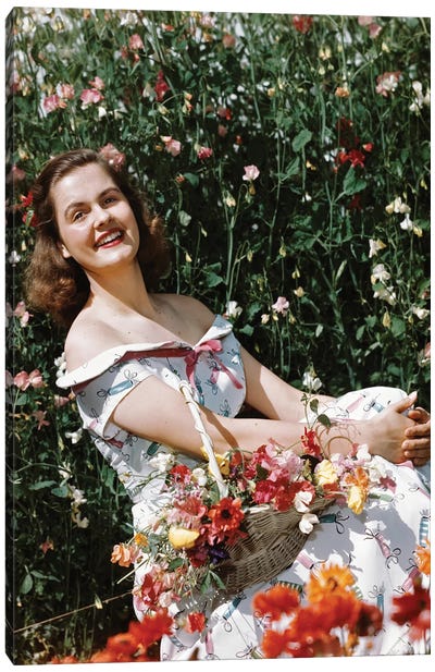 1950s Smiling Woman Sitting In Meadow Holding Basket Of Flowers Looking At Camera Canvas Art Print - Vintage Images