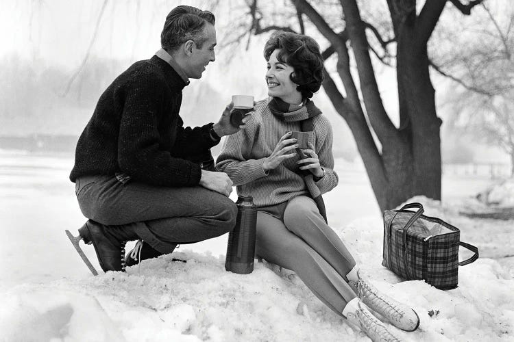 1960s Smiling Couple In Snow Wearing Ice Skates Drinking Hot Beverage From Thermos