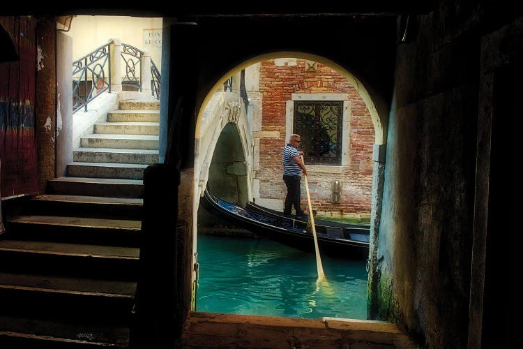 Gondolier Navigates Through A Venice Canal