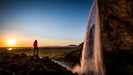 A Lone Figure In Front Of Seljalandfoss, Sudurland, Iceland, At Midnight by Alex Buisse